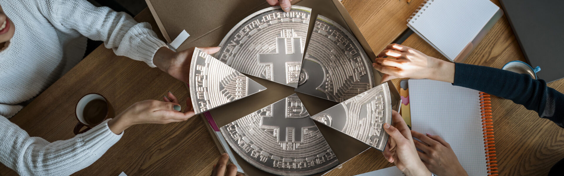 Business team dividing a Bitcoin-themed pizza, symbolizing shared investment and focus on key cryptocurrencies during market turbulence.