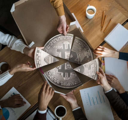 Business team dividing a Bitcoin-themed pizza, symbolizing shared investment and focus on key cryptocurrencies during market turbulence.