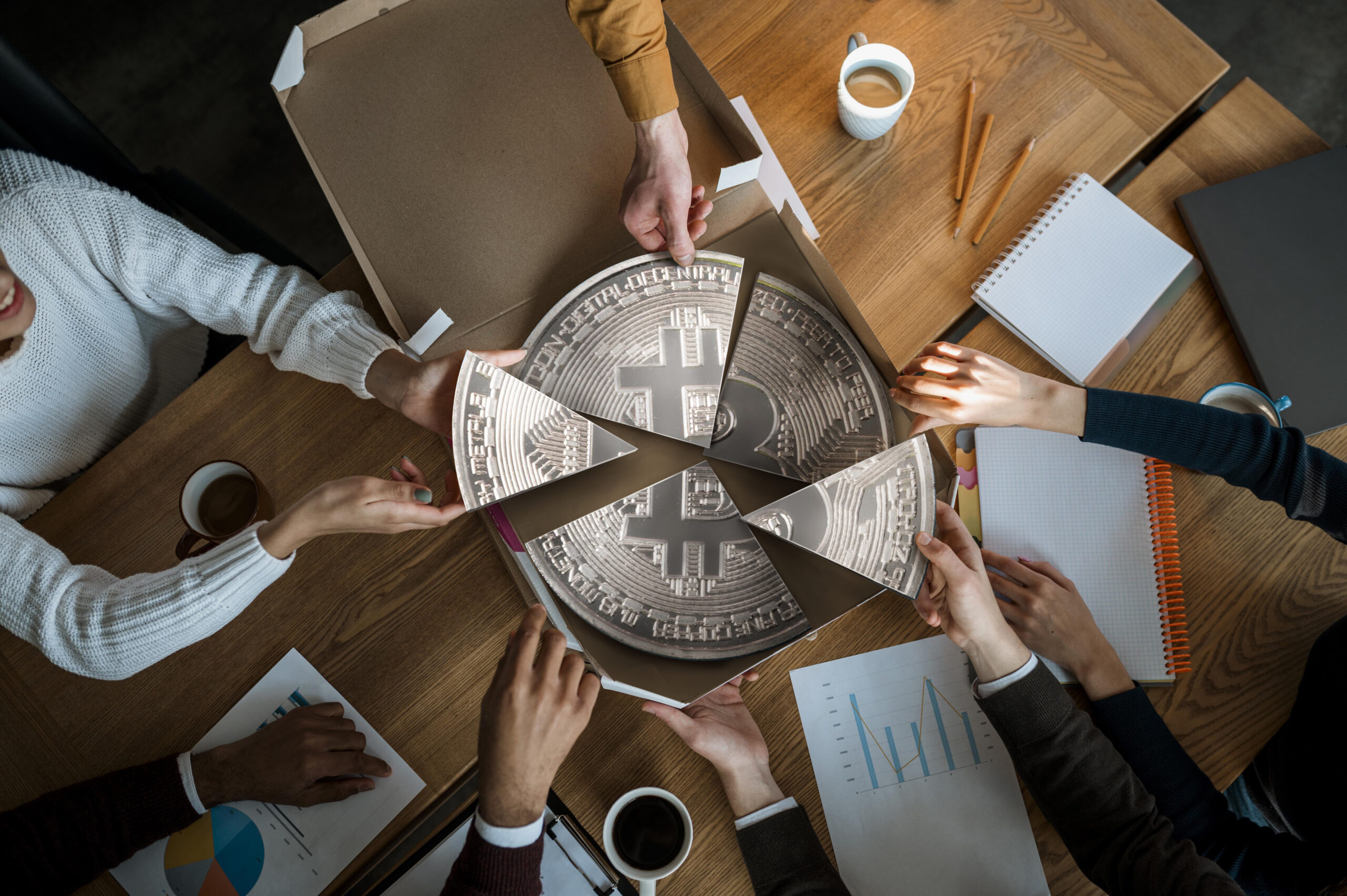 Business team dividing a Bitcoin-themed pizza, symbolizing shared investment and focus on key cryptocurrencies during market turbulence.
