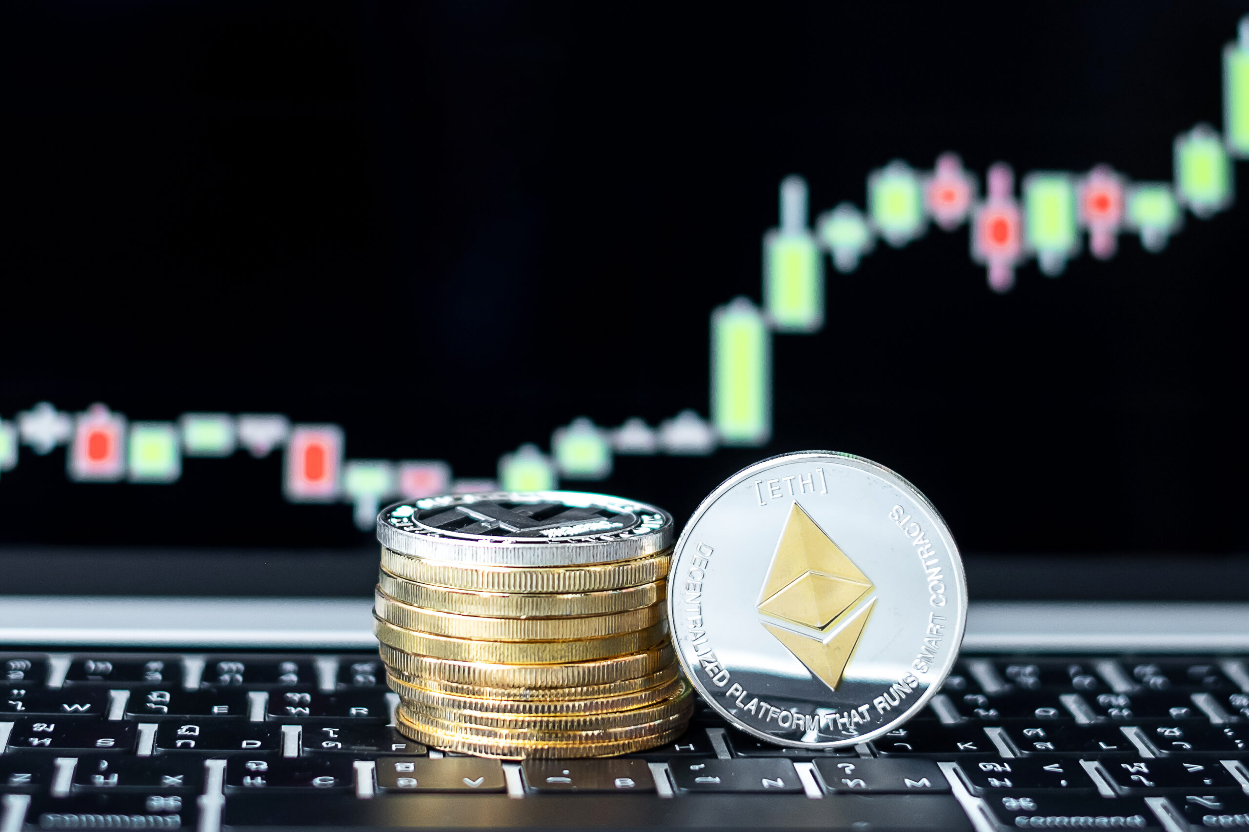 A close-up of stacked coins with a prominent silver Ethereum (ETH) token in focus, placed in front of a glowing candlestick chart showing market volatility and potential recovery trends.