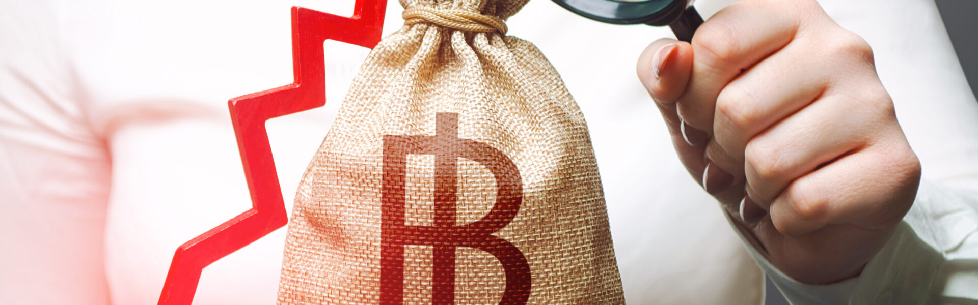 Woman holding a money bag with a Bitcoin symbol and a red downward arrow, symbolizing financial uncertainty and market decline.