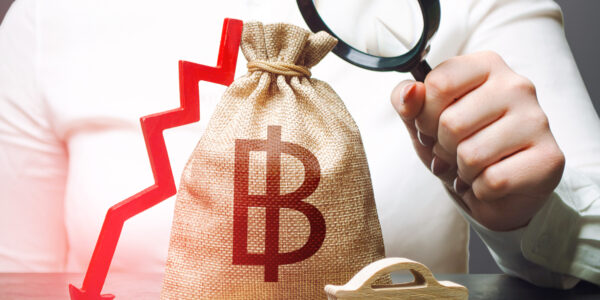 Woman holding a money bag with a Bitcoin symbol and a red downward arrow, symbolizing financial uncertainty and market decline.