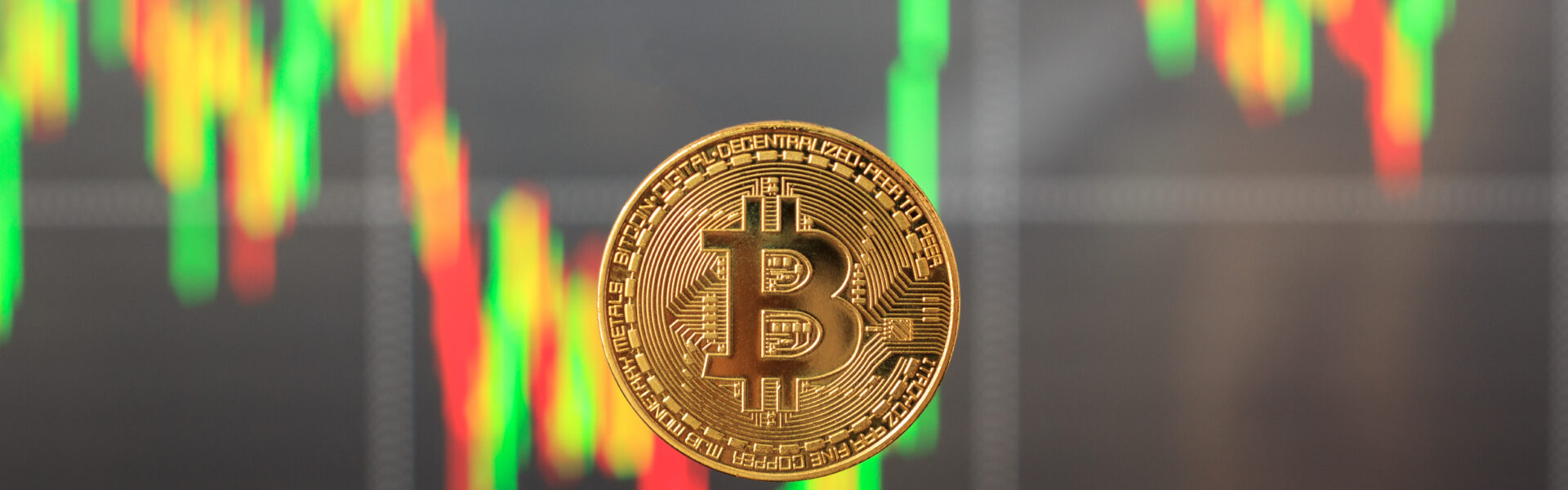 Single Bitcoin in focus with a blurred, falling candlestick chart in the background, symbolizing market panic and asset sell-offs.