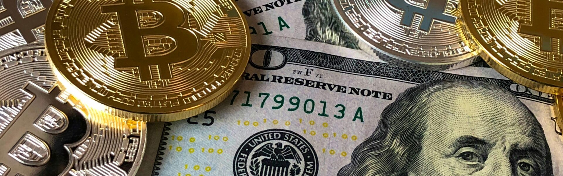 A close-up of gold Bitcoin coins placed on top of U.S. dollar bills, symbolizing the financial growth of Bitcoin startups amid a cooling crypto market.
