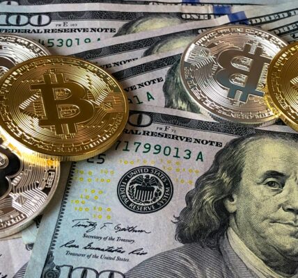A close-up of gold Bitcoin coins placed on top of U.S. dollar bills, symbolizing the financial growth of Bitcoin startups amid a cooling crypto market.