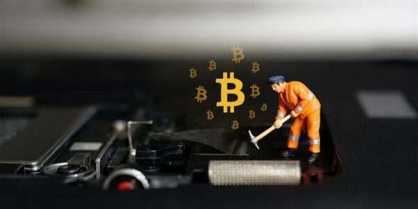 Miniature figure placing a glowing Bitcoin on a computer motherboard, representing Arizona’s growing support for digital mining rights.